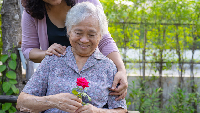 a senior citizen holding a red rose